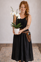 Woman holding a potted orchid plant with a neutral background