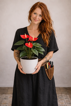 Woman holding a potted plant with red flowers against a plain background