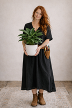 Woman holding a potted plant in a black dress with a neutral background