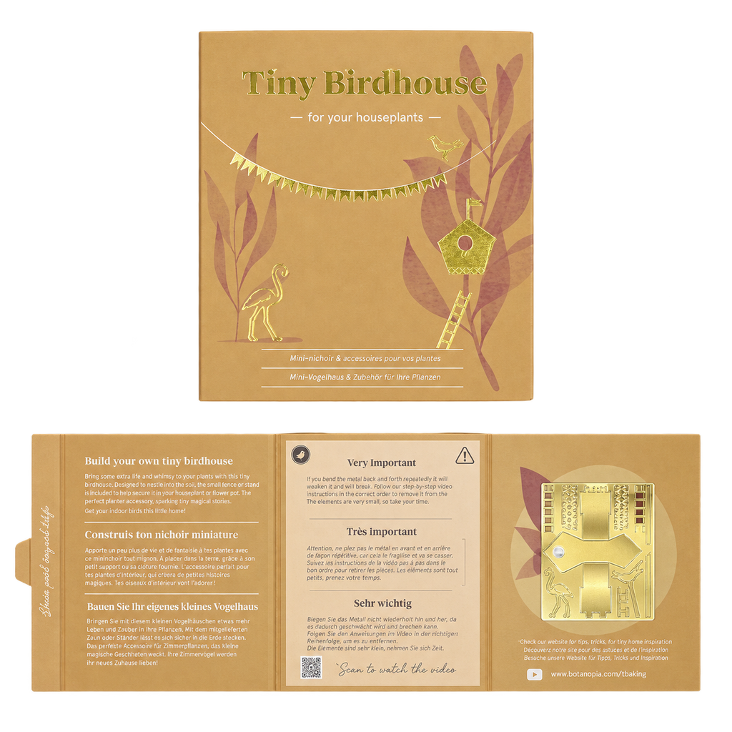 A product presentation of a 'Tiny Birdhouse' kit by Sea Otter Crafts, showing both the outer kraft paper packaging and the fully unfolded instruction booklet. The packaging is a warm tan color with gold foil accents and illustrations of a birdhouse and a deer.